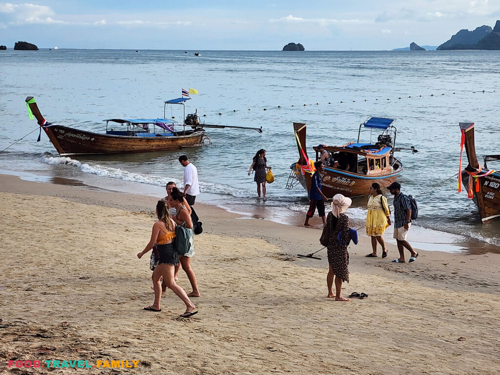 Tourists getting up and off long boats at Ao Nang Beach
